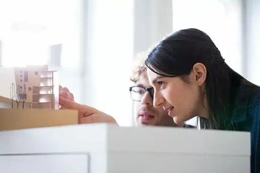 Two professionals focusing on a project model, discussing ideas and solutions.