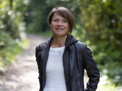 Professional trainer and coach smiling outdoors with natural background.