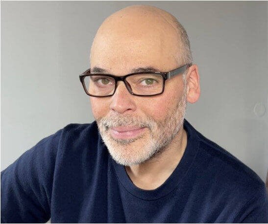 Professional coach smiling in a portrait against a neutral background.